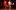 Clare Perkins in a red dress and Troy Glasgow in a white T and khaki joggers do a high kick while dancing