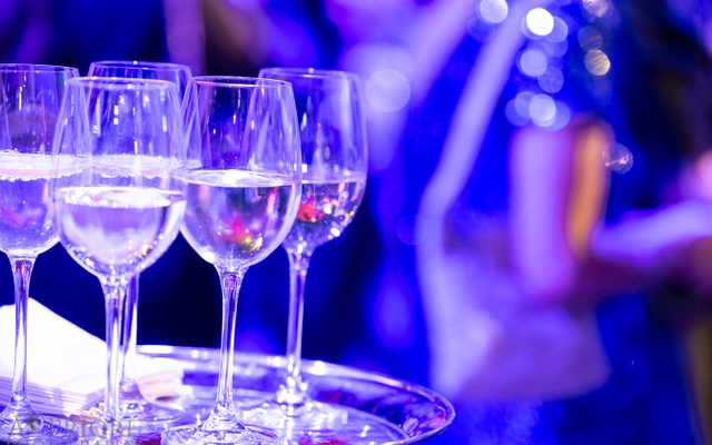 A tray of wine glasses bathed in purple light.